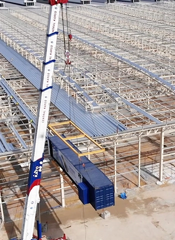 A crane lifts a large metal structure onto a partially completed Proton factory in Tanjung Malim, showcasing Thung Hing's TH R505 Standing Seam Metal Roofing.