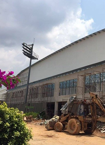 Partially constructed sports centre in Kompleks Sukan Bukit Kiara, Kuala Lumpur, featuring TH Clip Lock Optima 730 (PPGI) roofing system, with scaffolding and a construction vehicle.